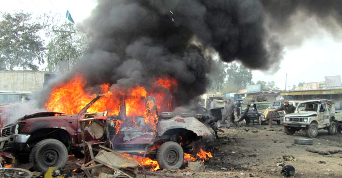 Residents run past a burning vehicle after a car bomb attack in the Pakistani town of Jamrud on December 17. – Photo by AFP
