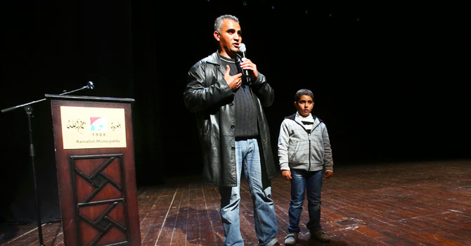 Palestinian journalist Emad Burnat stands next to his son Jibril as he speaks to the audience after a screening of his Oscar-nominated documentary '5 Broken Cameras' in the West Bank city of Ramallah. —Photo by Reuters