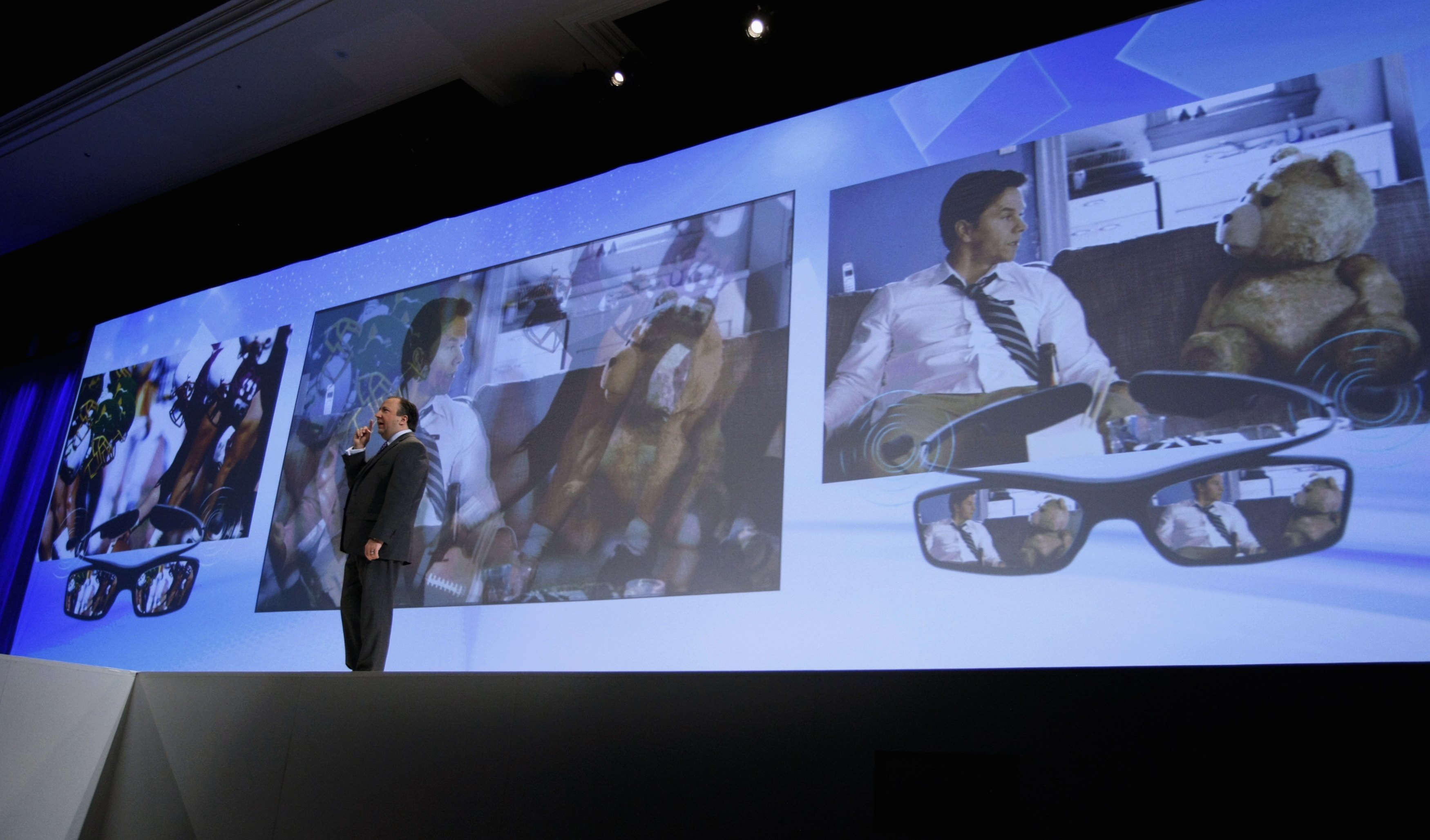 Joe Stinziano, executive vice-president for Samsung Electronics America, demonstrates a new television that shows two programs at once at the Samsung news conference at the Consumer Electronics Show (CES) in Las Vegas January 7, 2013. Two people can watch two programs on the same TV using special glasses (seen at right). REUTERS/Rick Wilking (UNITED STATES - Tags: BUSINESS SCIENCE TECHNOLOGY)