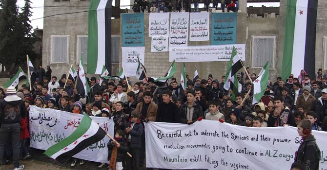 Youths hold banners and wave Syrian opposition flags during a protest against Syria's President Bashar al-Assad, in Jabal Al-Zawiya near Idlib, in this picture provided by Shaam News Network and taken Jan 11, 2013. Picture taken Jan 11, 2013. - Reuters