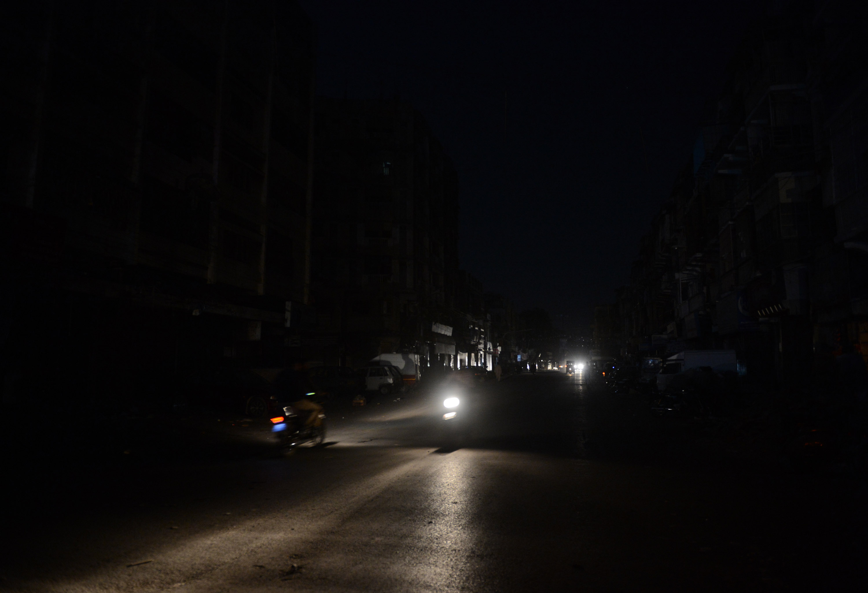 This picture taken on February 24, 2013 shows Pakistani commuters driving on a street in a residential area during a nationwide power blackout in Karachi.  Pakistan was hit by a nationwide blackout for more than two hours after the breakdown of a major plant caused power stations to stop working across the country, officials said on February 25.  AFP PHOTO/Asif HASSAN