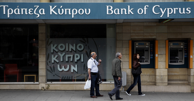 People pass by a branch of the bank of Cyprus in central capital Nicosia, Cyprus, on Saturday, March 30, 2013. Big depositors at Cyprus' largest bank may be forced to accept losses of up to 60 percent, far more than initially estimated under the European rescue package to save the country from bankruptcy, officials said Saturday. (AP Photo/Petros Karadjias)