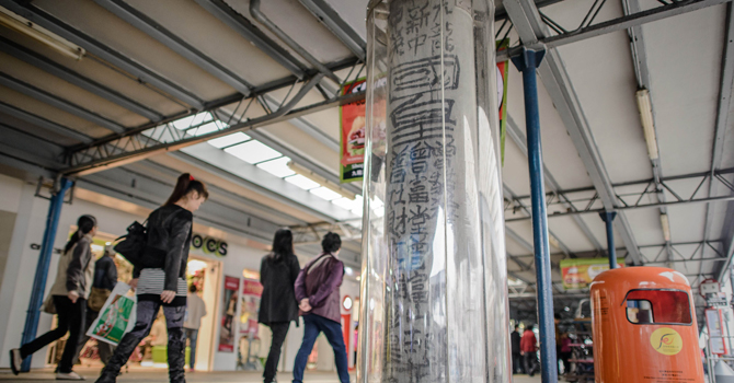 Pedestrians walk past a plastic casing set up around a graffiti made by the late self-declared “King of Kowloon”, Tsang Tsou-choi, in Hong Kong. —Photo by AFP