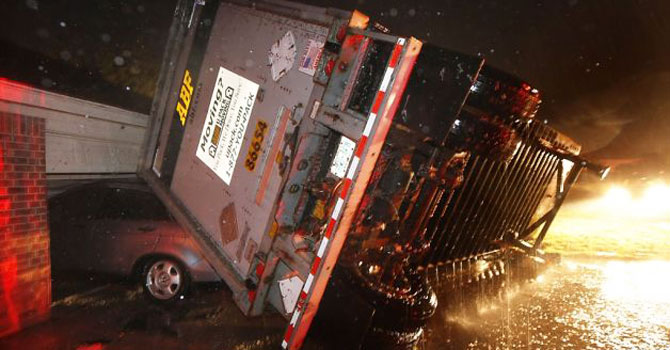 A trucking company trailer landed on a car that was parked in front of a Lindsey Ln. home in Cleburne Texas after a powerful storm went through Wednesday night, May 15, 2013. Neighbors say the trailer was parked on the street and was rolled over onto the car. —AP Photo