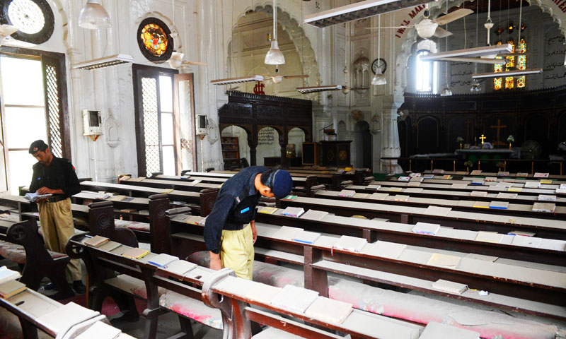 Police officials search for evidence among the dust covered pews of the All Saints Church in Peshawar where two bomb blasts occurred, killing 81 people. -Photo by AFP