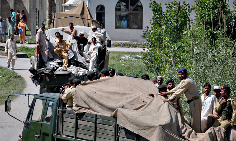 Soldiers and residents stand over covered debris as it is moved out by military vehicles from the compound within which Al Qaeda leader Osama bin Laden was killed, in Abbottabad. —Photo by Reuters