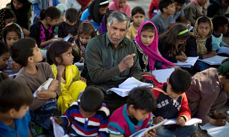 اٹھارہ مارچ کی اس تصویر میں محمد ایوب غریب بچوں کو پڑھا رہے ہیں&mdash; اے پی فوٹو