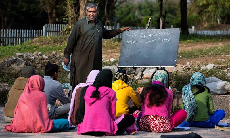 محمد ایوب اسلام آباد کے ایک پارک میں قائم عارضی اسکول میں بچوں کو پڑھاتے ہوئے&mdash; اے پی فوٹو