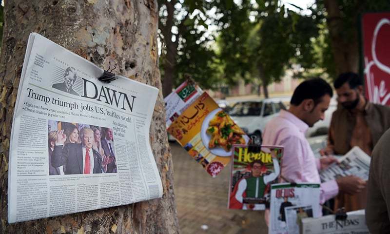 Pakistani residents read newspapers with coverage of Donald Trump&#39;s victory in the US presidential election in Islamabad. ─ AFP