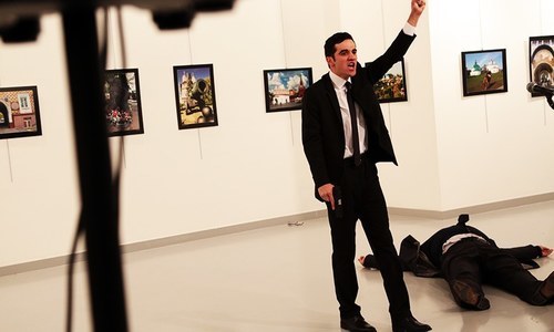 A man gestures near to the body of a man at a photo gallery in Ankara. -AP
