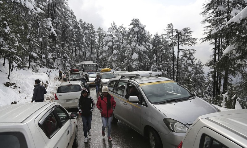 Passengers walk past vehicles stranded due to heavy snow fall on the Jammu-Srinagar highway at Patnitop. ─AP