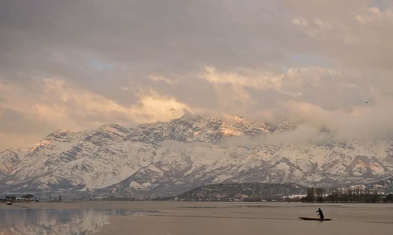 A man paddles his boat on the half frozen Dal Lake in Srinagar. ─AFP