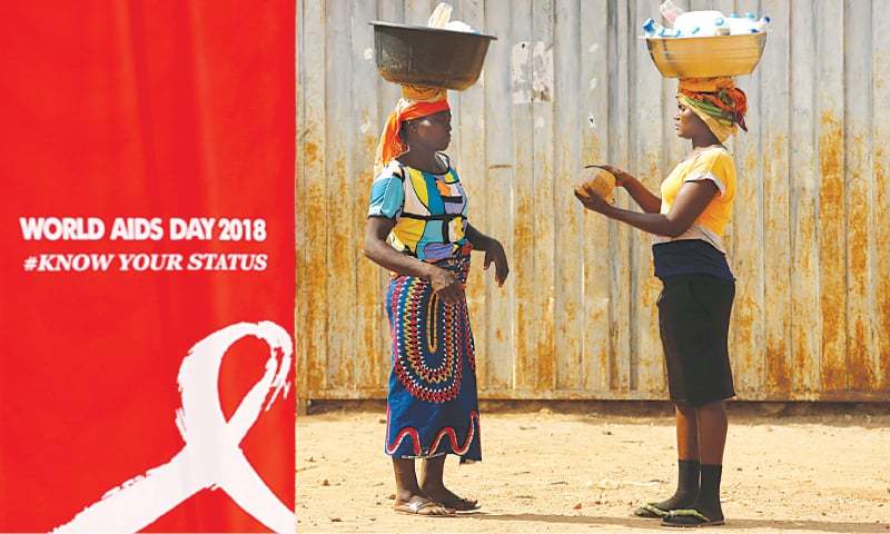 Abuja: Women stand near a banner during an HIV AIDS awareness campaign on the occasion of World AIDS Day at the Kuchingoro IDPs camp on Saturday.—Reuters