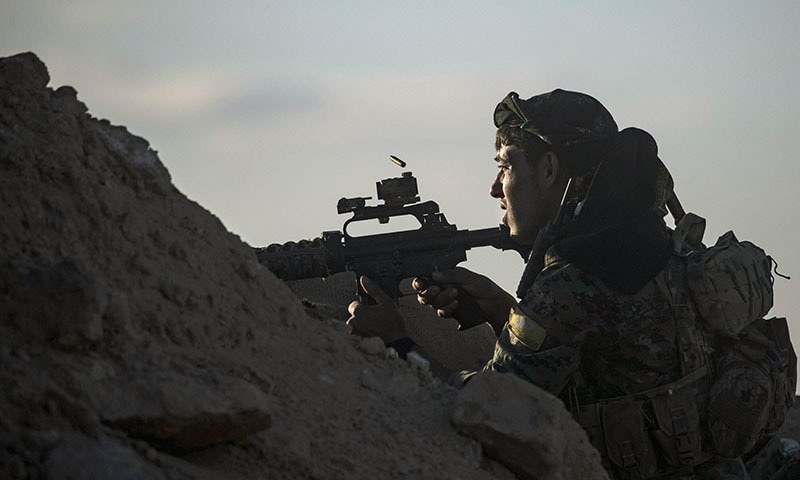 A fighter with the Syrian Democratic Forces keeps position at a hilltop as he watches the Islamic State group's last remaining location in the village of Baghouz