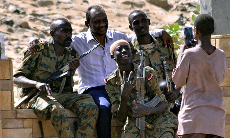 Sudanese military officers and a demonstrator pose for a photograph in celebration after Defence Minister Awad Ibn Auf stepped down as head of the country's transitional ruling military council, as protesters demanded quicker political change, near the Defence Ministry in Khartoum. â Reuters