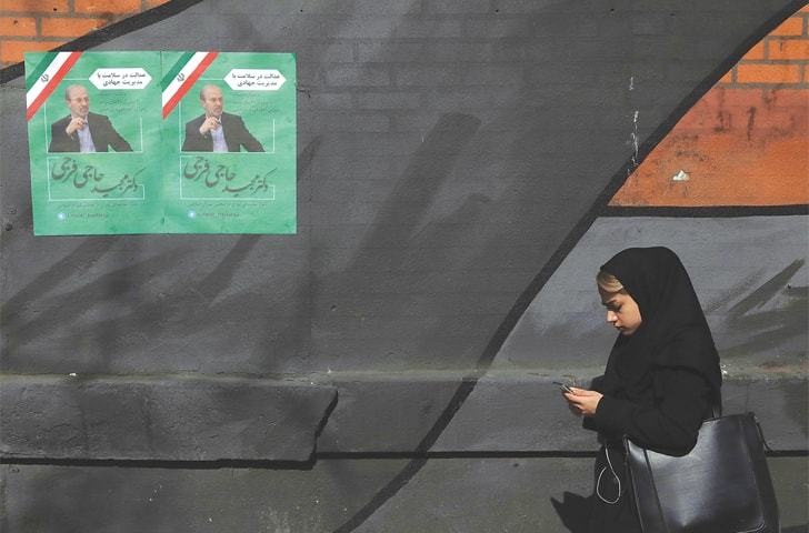 Tehran: A pedestrian walks past campaign posters for parliamentary election candidate Majid Hajifaraji on Thursday.—AP