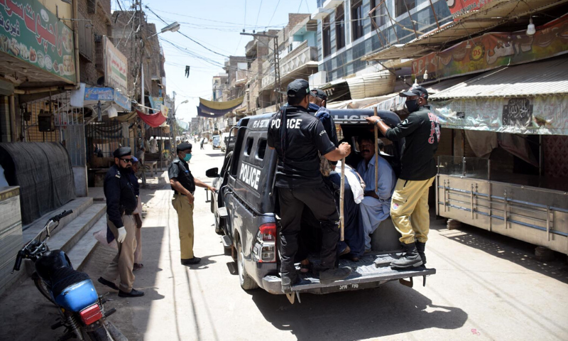 پولیس اہلکار دکانداروں کو گرفتار کر رہے ہیں جنہوں نے لاک ڈاؤن کی خلاف ورزی کی۔ – فوٹو:عمیر علی