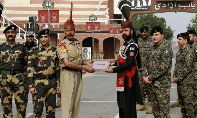 Indian Border Security Force (BSF) soldier (centre L) receives sweets from Pakistan's Rangers soldier (centre R) on the occasion of the Eidul Azha at the India-Pakistan Wagah border post. &mdash; AFP