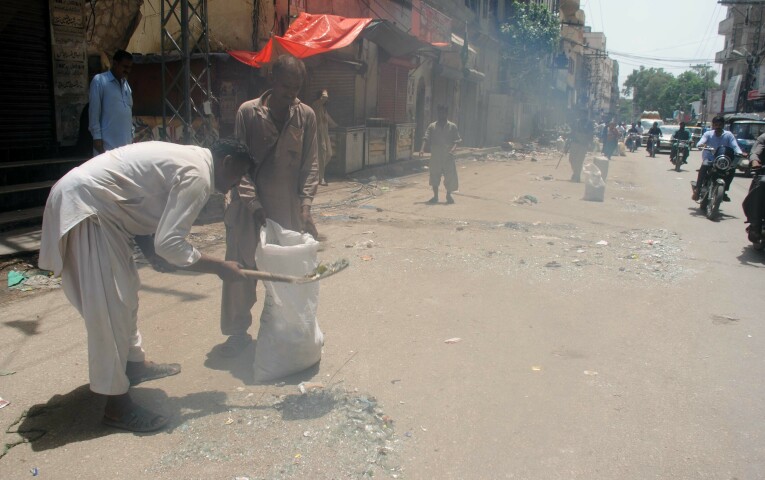 Trash pickers and labourers collect glass strewn on the ground. — Photo courtesy: Umair Ali