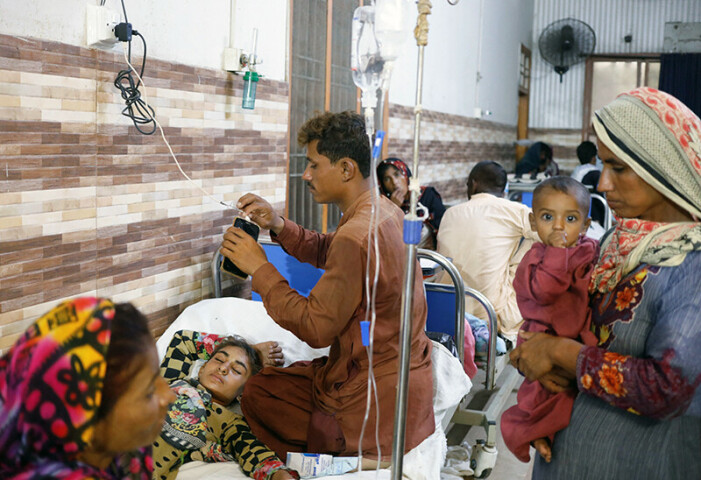  A man charges his phone as a woman affected by the floods and suffering from malaria and fever lies on a bed and waits for medical assistance, in a corridor at Sayed Abdullah Shah Institute of Medical Sciences in Sehwan, Pakistan September 29, 2022. — Reuters