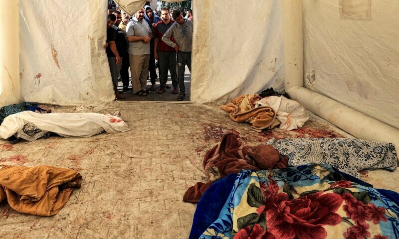 The bodies of victims of the overnight strike at the Ahli Arab hospital are placed in a makeshift tent at the site in central Gaza on October 18, 2023. &mdash; AFP