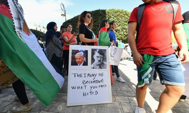 A demonstrator stands with a sign showing the faces of Israeli Prime Minister Benjamin Netanyahu and Nazi Germany&rsquo;s leader Adolf Hitler during a rally in solidarity with Palestinians. &mdash; AFP