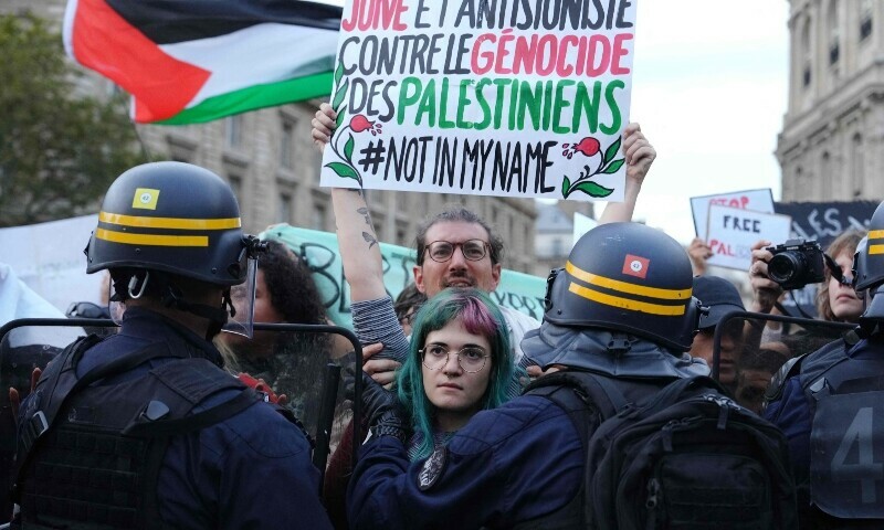 A protester holds a placard reading &ldquo;Jewish and anti-Zionist against the genocide of the Palestinians, not in my name&rdquo; as protesters face riot police officers during a demonstration in support of Palestinians at Place de la Republique during in Paris. &mdash; AFP