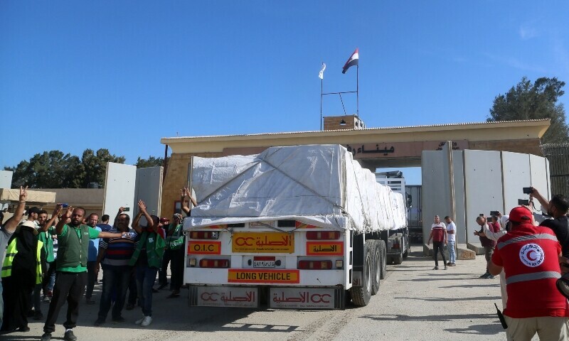 People on the Egyptian side of the Rafah border crossing watch as a convoy of lorries carrying humanitarian aid crosses to the Gaza Strip on October 21, 2023. &mdash;AFP