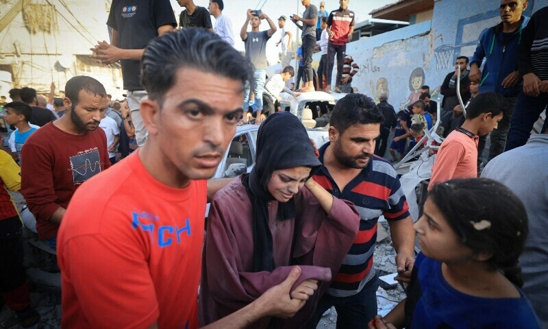 Palestinians evacuate a wounded woman after an Israeli strike near an United Nations Relief and Works Agency for Palestine Refugees. &mdash; AFP