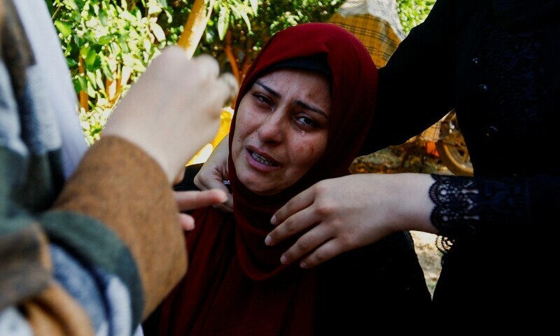A child looks on from behind a gate as mourners react near the bodies of Palestinians killed in Israeli strikes during their funeral, in Khan Younis in the southern Gaza Strip on October 31. &mdash; Reuters