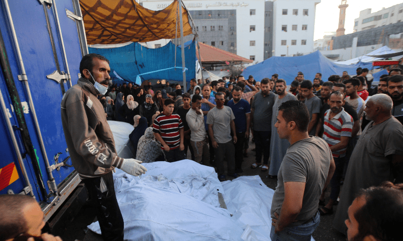  People surround the bodies of people killed a day earlier in an Israeli strike that hit the entrance of Al-Shifa hospital in Gaza City, during a funeral held for the victims on November 4. &mdash; AFP 