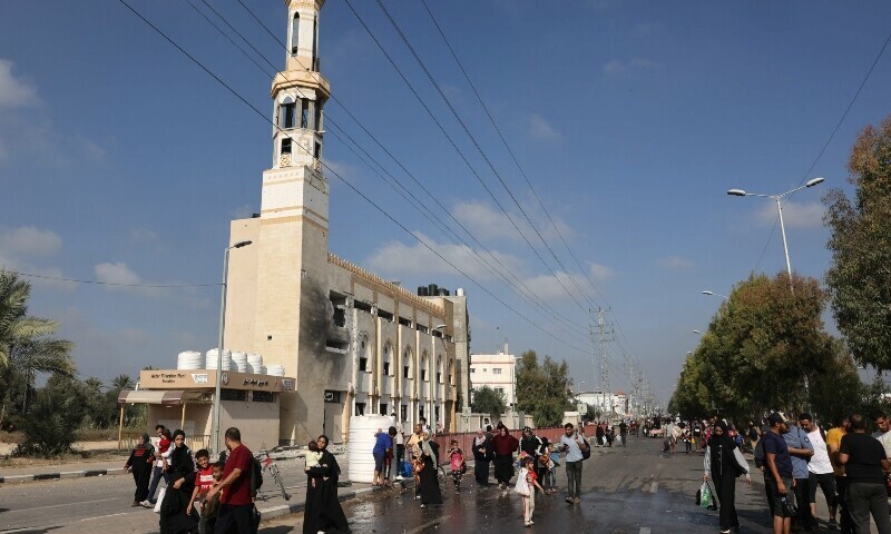 Palestinians walk past a damaged mosque as they flee Gaza City and other parts of northern Gaza towards the southern areas on November 8. &mdash; AFP