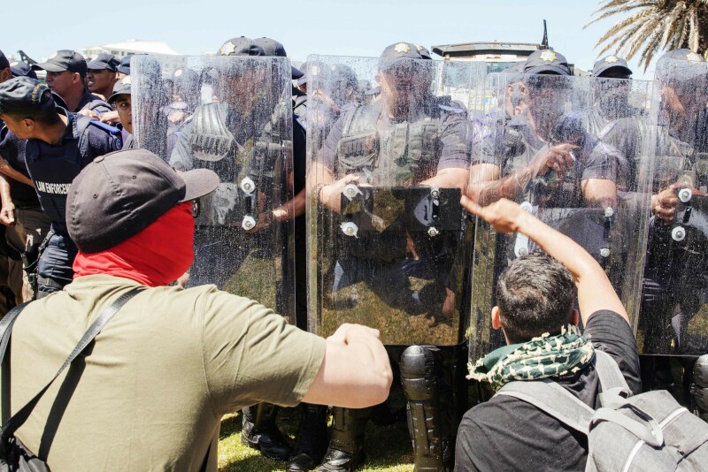 Cape Town Metro Police Department (CTMPD) officers line up as pro-Palestinian supporters gesture towards them in Cape Town on November 12. — AFP