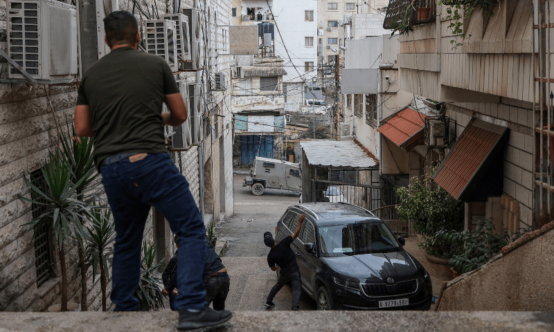 Palestinian youths throw stones towards an Israeli forces’ armoured vehicle during a military operation in Tulkarem in the occupied West Bank on Nov 14, 2023. — AFP