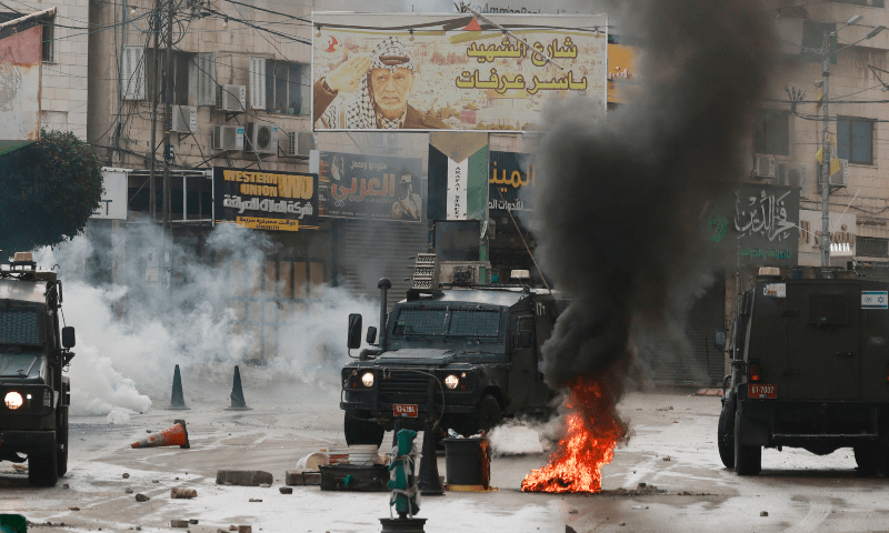 White smoke from tear gas fired by Israeli troops spreads behind burning tyres on a barricaded street during clashes between Israeli forces and Palestinian youths as a military operation was conducted in the occupied West Bank city of Tulkarem on Nov 14, 2023. — AFP