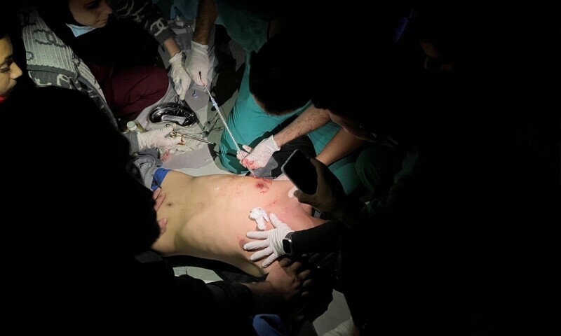 Medics use phone flashlights to assist a Palestinian wounded in Israeli strikes at the Indonesian hospital in the northern Gaza Strip on November 16. &mdash; AFP