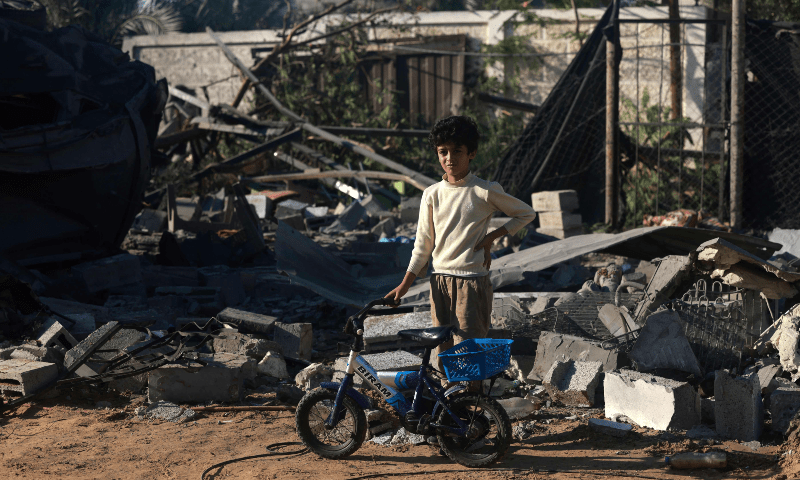  A Palestinian boy stands next to his bike in front of the debris of a house following an Israeli strike in Rafah in the southern Gaza Strip on Nov 18, 2023 &mdash; AFP 