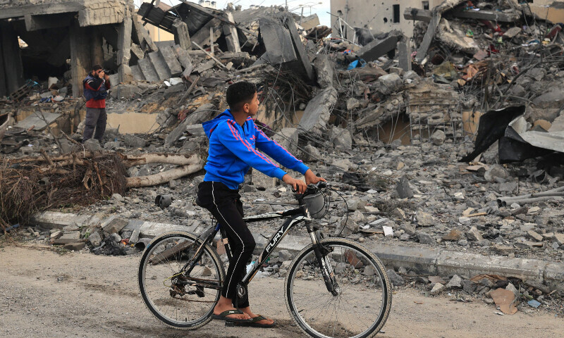 A Palestinian boy on a bicycle looks at rubble of a building following Israeli strikes in Rafah in the southern Gaza Strip on November 22, 2023. &mdash;AFP
