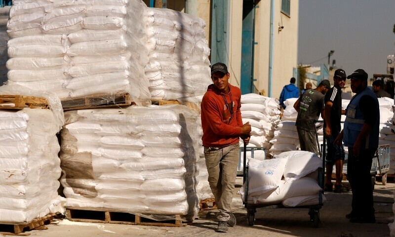 A man pulls a cart with flour bags as Palestinians gather to receive flour distributed by UNRWA in Rafah. &mdash; Reuters