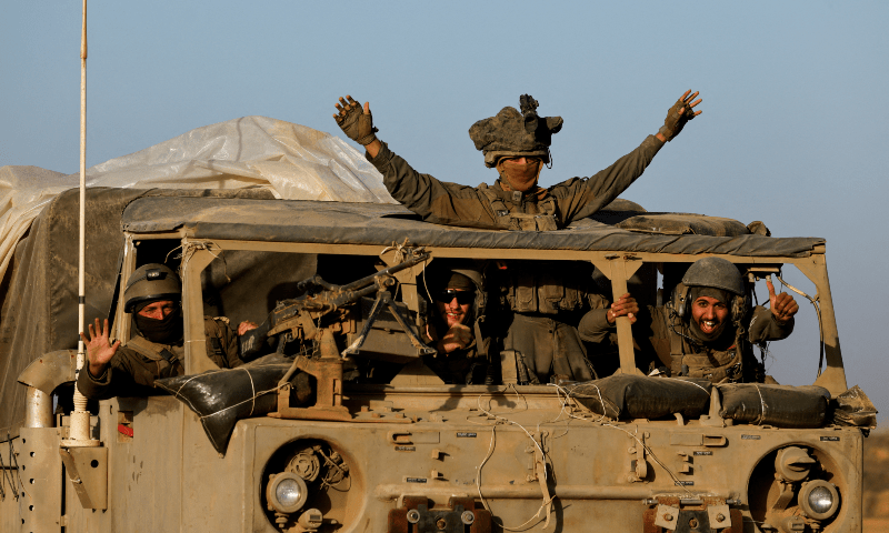  Israeli soldiers react from a military vehicle while driving by Israel&rsquo;s border after leaving Gaza, in Israel on Nov 24, 2023. &mdash; Reuters 