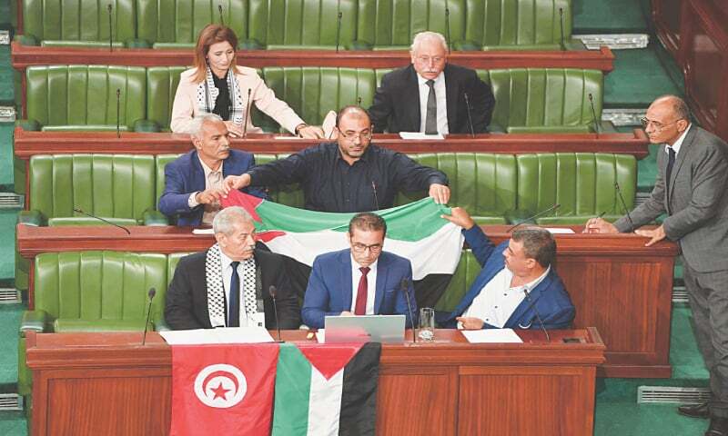Members of Tunisia’s parliament hold the Palestinian flag as they observe a minute of silence for civilian deaths in the Gaza Strip.—AFP