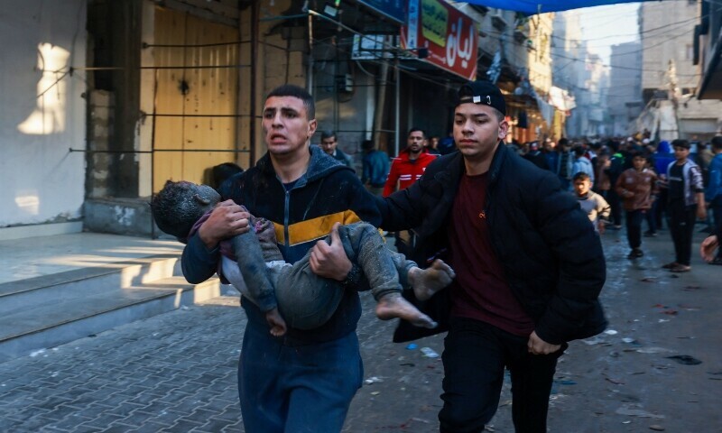 A Palestinian man carries an injured boy following the resumption of Israeli bombardment in Rafah, southern Gaza Strip, on December 1, 2023. &mdash; AFP