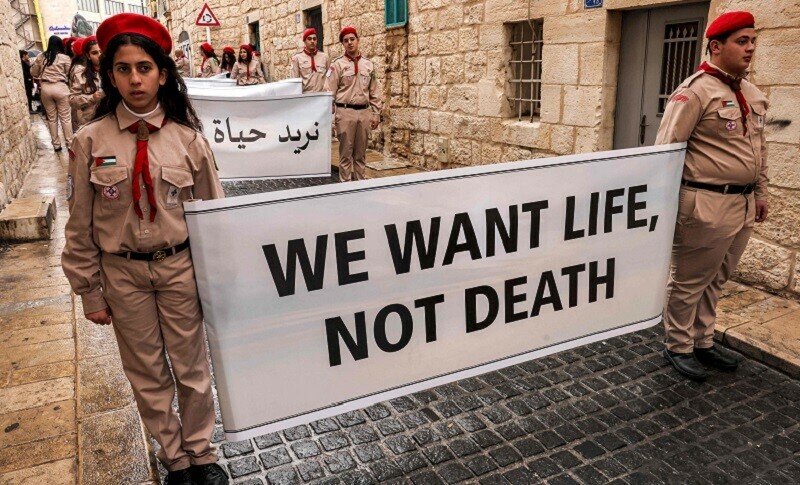 Palestinian youth members of the scouting movement hold up banners condemning and calling for an end of the conflict in the Gaza Strip between Israel and Hamas in the occupied West Bank on Dec 24, 2023. &mdash; AFP