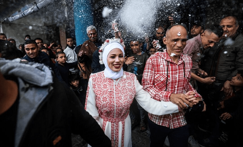 Palestinian bride Afnan Jibril (C) is escorted by her father (C-R) during her wedding at the UNRWA School in the al-Salam neighborhood of Rafah, southern Gaza Strip. &mdash; AFP