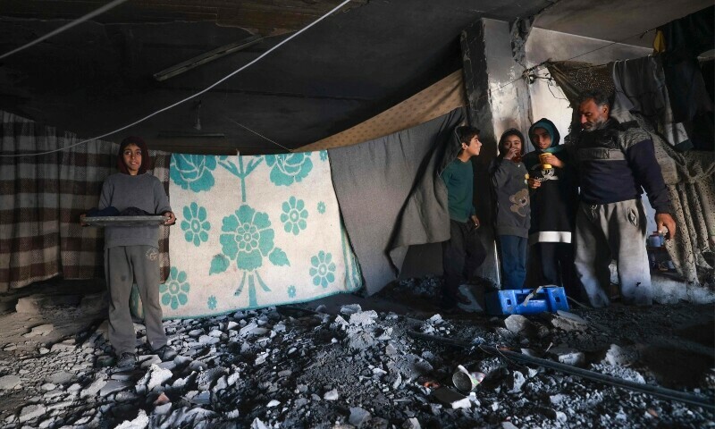 A displaced Palestinian family stand in their makeshift shelter inside a building damaged during Israeli bombardment in Rafah in the southern Gaza Strip on January 17, 2024. &mdash; AFP