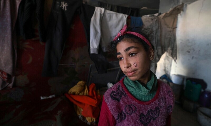 A displaced Palestinian girl poses for a picture as she shelters with her family inside a building damaged during Israeli bombardment in Rafah in the southern Gaza Strip on January 17, 2024. &mdash; AFP