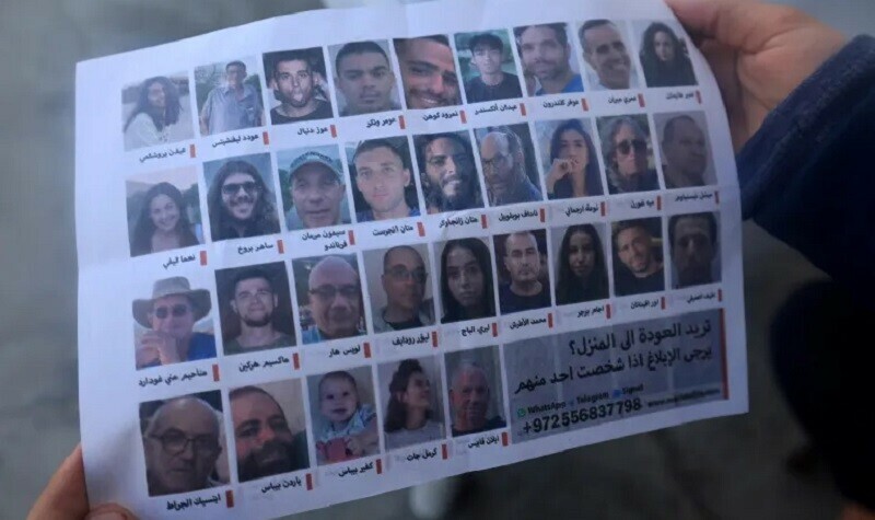 A man holds one of the leaflets, which were dropped by Israeli forces over the city, showing portraits of Israeli hostages held in Gaza. &mdash; AFP