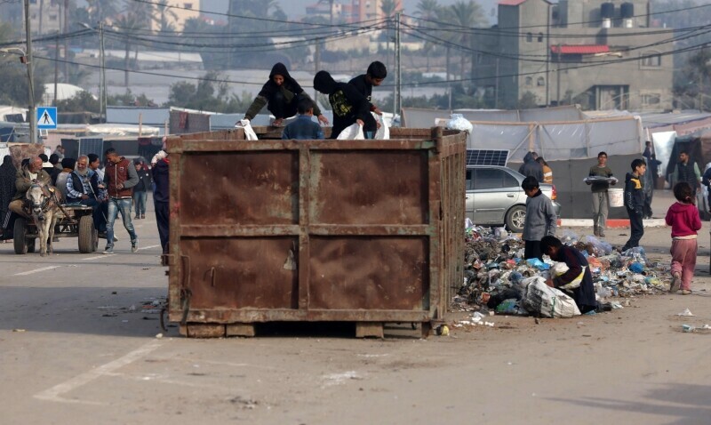 Displaced Palestinians search a garbage bin at a makeshift tent camp in Rafah near the border with Egypt in the southern Gaza Strip, on January 21. &mdash; AFP