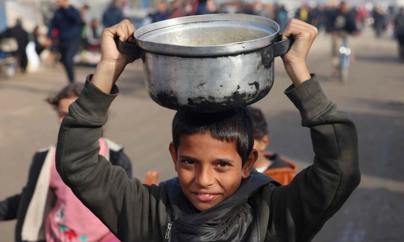 Displaced Palestinian youths carry food rations they received at a makeshift tent camp in Rafah near the border with Egypt in the southern Gaza Strip on January 21, 2024. &mdash; AFP