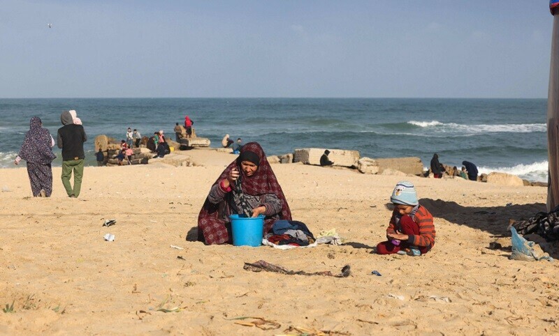  A woman washes clothes in a bucket at a makeshift tent camp for displaced Palestinians in Rafah near the border with Egypt. &mdash; AFP